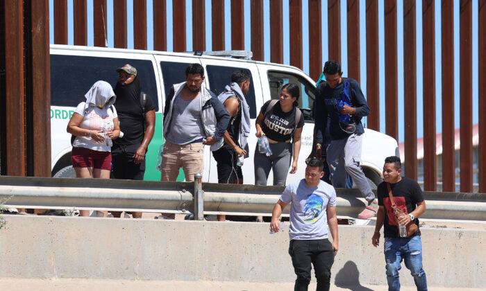 Ciudadanos venezolanos caminan a lo largo del muro fronterizo hacia una camioneta de la Patrulla Fronteriza que los espera luego de cruzar ilegalmente el Río Grande desde México, en El Paso, Texas, el 21 de septiembre de 2022. (Joe Raedle/Getty Images)