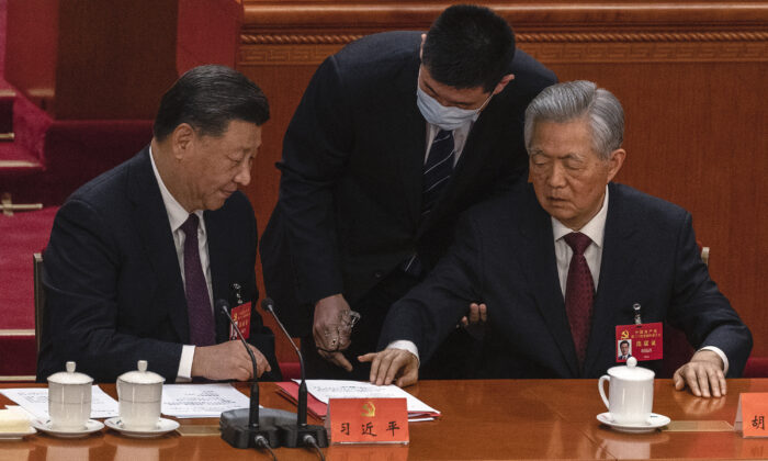 El líder chino Xi Jinping mira al exlíder Hu Jintao (Der.) mientras le ayudan a salir anticipadamente de la sesión de clausura del 20º Congreso del Partido Comunista Chino en el Gran Salón del Pueblo en Beijing, el 22 de octubre de 2022. (Kevin Frayer/Getty Images)