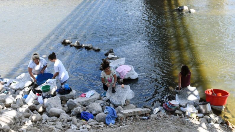 Mujeres lavan ropa y platos en las aguas contaminadas del río Lempa en Citala, a 100 kilómetros al norte de San Salvador (El Salvador) el 4 de febrero de 2017. (Marvin Recinos/AFP vía Getty Images)