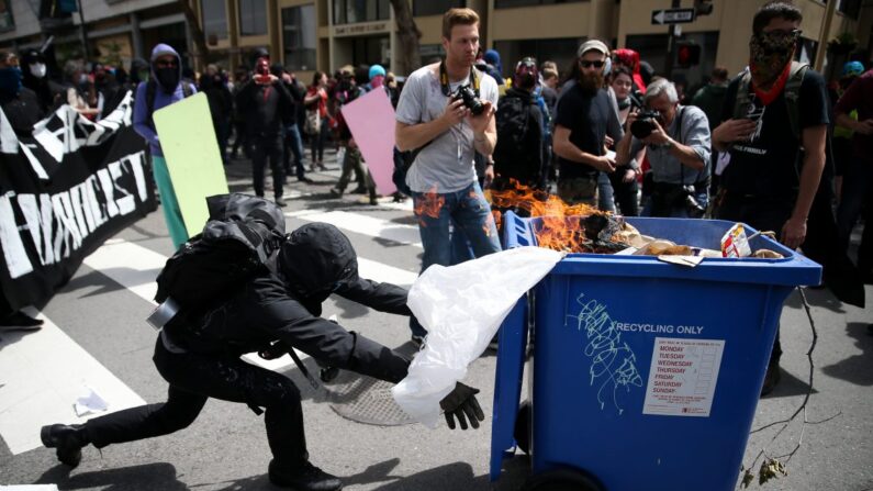 Un extremista Antifa empuja un contenedor de reciclaje en llamas contra los partidarios de Trump durante una manifestación por la libertad de expresión en Berkeley, California, el 15 de abril de 2017. (Elijah Nouvelage/Getty Images)
