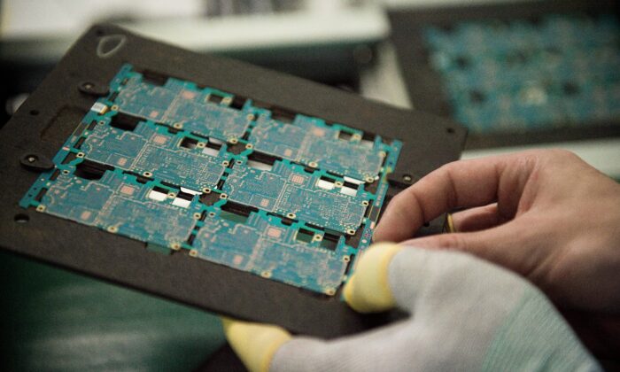 Los circuitos de componentes de chips de teléfonos inteligentes son manejados por un trabajador en la fábrica de Oppo, en Dongguan, el 8 de mayo de 2017. (NICOLAS ASFOURI/AFP a través de Getty Images)
