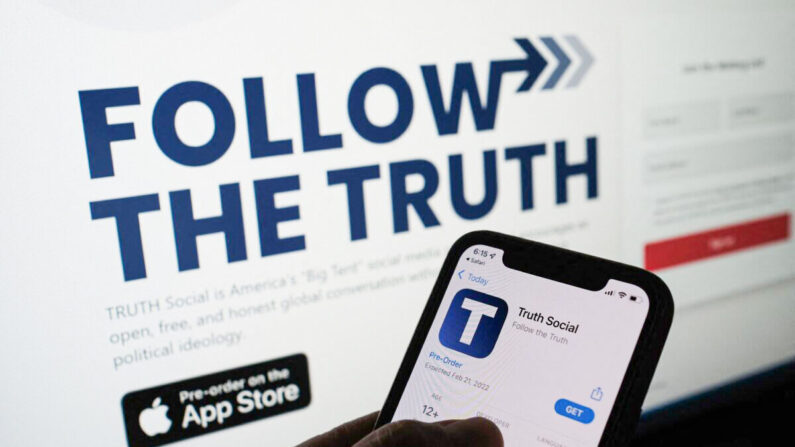 Esta foto ilustrativa muestra a una persona revisando la tienda de apps en un smartphone para "Truth Social" —propiedad de Trump Media & Technology Group— con su sitio web en la pantalla de un ordenador en el fondo, en Los Ángeles, el 20 de octubre de 2021. (Chris Delmas/AFP vía Getty Images)
