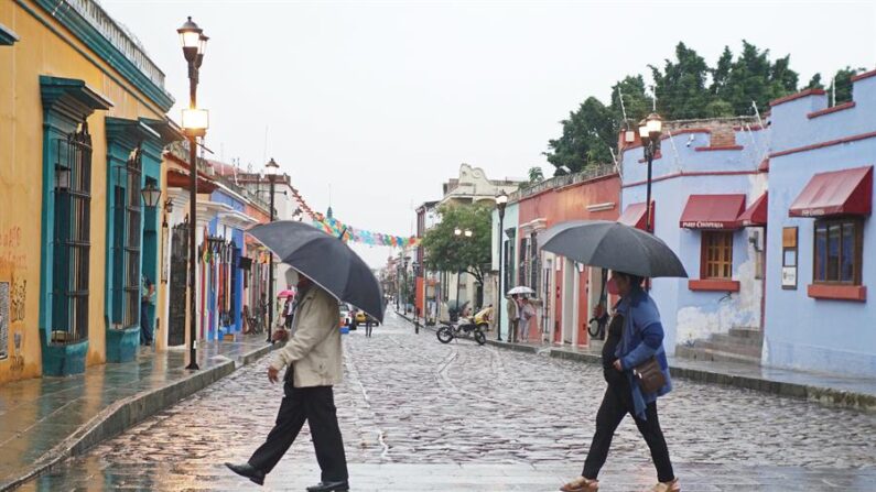 Dos personas se protegen de la lluvia en el estado de Oaxaca (México). EFE/Daniel Ricardez/Archivo