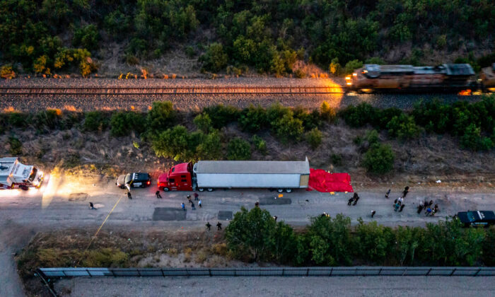 Agentes de la ley investigan un tractor-remolque que transportaba inmigrantes ilegales con decenas de muertos en su interior, en San Antonio, el 27 de junio de 2022. (Jordan Vonderhaar/Getty Images)