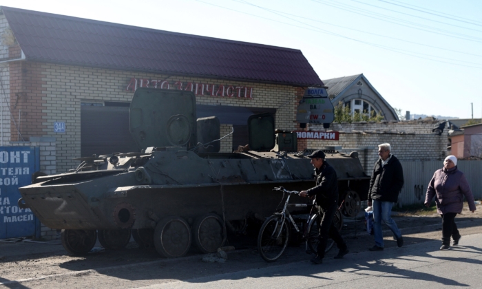Residentes locales pasan por delante de un vehículo blindado de personal ruso destruido en la ciudad de Kupiansk, región de Járkov, el 17 de octubre de 2022, en medio de la invasión militar rusa de Ucrania. (Anatolii Stepanov/AFP vía Getty Images)