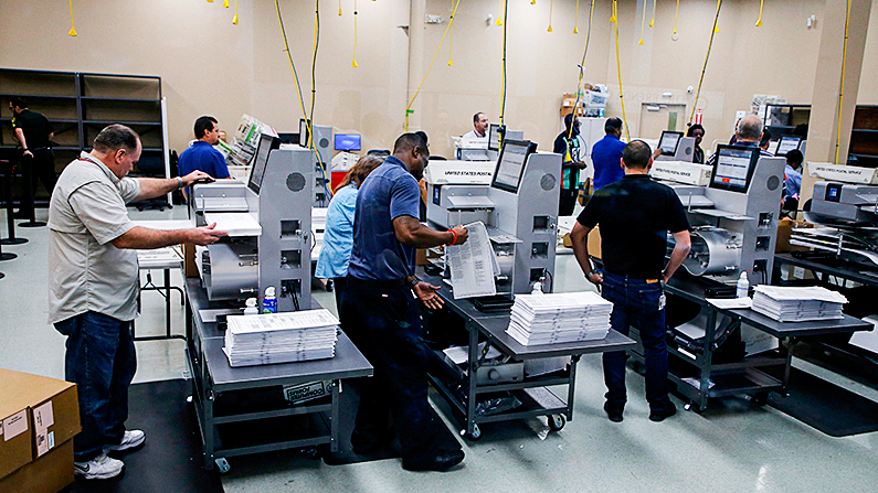 El personal electoral carga las boletas en las máquinas mientras comienza el recuento en la Oficina del Supervisor de Elecciones del condado de Broward en Lauderhill, Florida, el 11 de noviembre de 2018. (Joe Skipper/Getty Images)