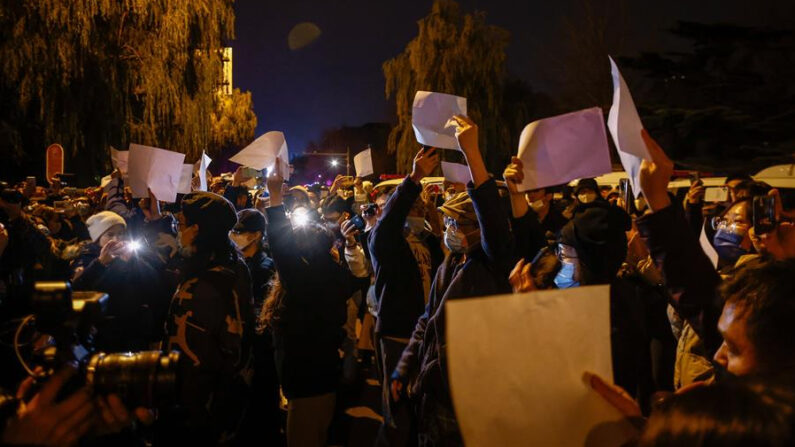 Manifestantes agitan papeles blancos en una protesta en Beijing tras un incendio en Urumqi que mató a 10 personas. EFE/EPA/Mark R. Cristino