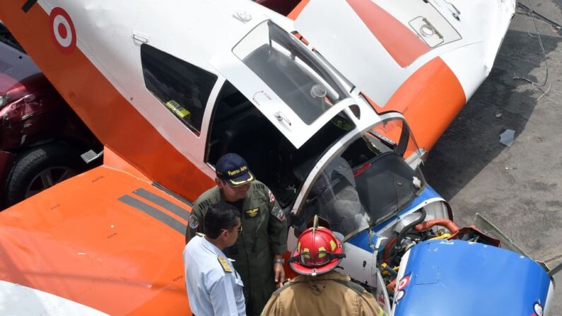 En una fotografía de archivo, bomberos, policías y miembros de la Fuerza Aérea se encuentran en el lugar donde un avión de entrenamiento de la Fuerza Aérea del Perú se estrelló en una calle de Lima el 4 de febrero de 2019. (Cris Bouroncle/AFP vía Getty Images)