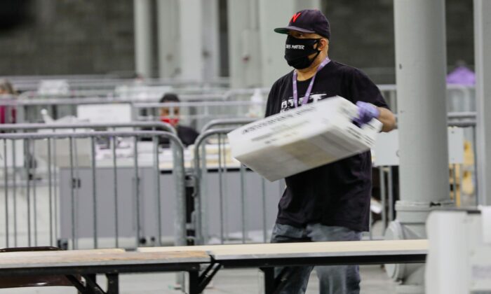 Durante la segunda vuelta de las elecciones al Senado de Georgia, un trabajador lleva un contenedor de boletas para escanear en el Centro de Congresos Mundial de Georgia en Atlanta, Georgia, el 5 de enero de 2021. (Sandy Huffaker/AFP a través de Getty Images)