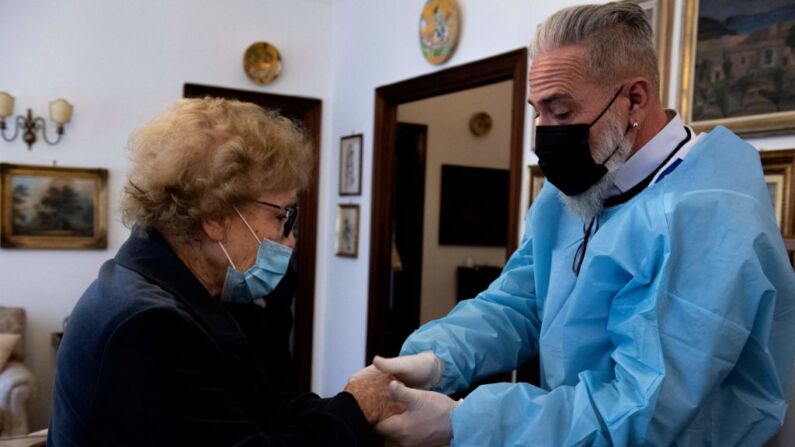 Un médico de la Autoridad Sanitaria Local ASL Roma 1, sostiene la mano de Adriana, de 91 años, luego de que recibiera una dosis de la vacuna contra el coronavirus COVID-19 de Pfizer-BioNTech de una dosis, como parte de una campaña de vacunación a domicilio para personas mayores llevada a cabo por la ASL, el 14 de abril de 2021 en Roma, durante la pandemia del coronavirus COVID-19. (Foto de TIZIANA FABI/AFP vía Getty Images)
