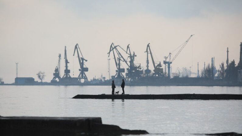 Una pareja pasea a un perro en un muelle de la costa del mar de Azov en la ciudad portuaria industrial ucraniana de Mariupol el 23 de febrero de 2022. (Aleksey Filippov/AFP vía Getty Images)