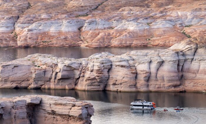 Un barco se abre paso a través de una formación rocosa cada vez más visible a medida que baja el nivel del lago Powell, cerca de la presa de Glen Canyon en el río Colorado en Page, Arizona, el 1 de septiembre de 2022. (ROBYN BECK/AFP vía Getty Images)