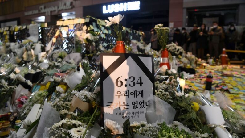 Un cartel con la hora 6:34 (PM), que hace referencia a la primera llamada realizada a la policía en la noche del mortal atropello de Halloween en el que murieron 156 personas, seguido de "No había país para nosotros", se muestra entre las flores dejadas en un monumento improvisado para las víctimas, fuera de una estación de metro en el distrito de Itaewon en Seúl (Corea del Sur) el 5 de noviembre de 2022. (Kang Jin-kyu/AFP vía Getty Images)