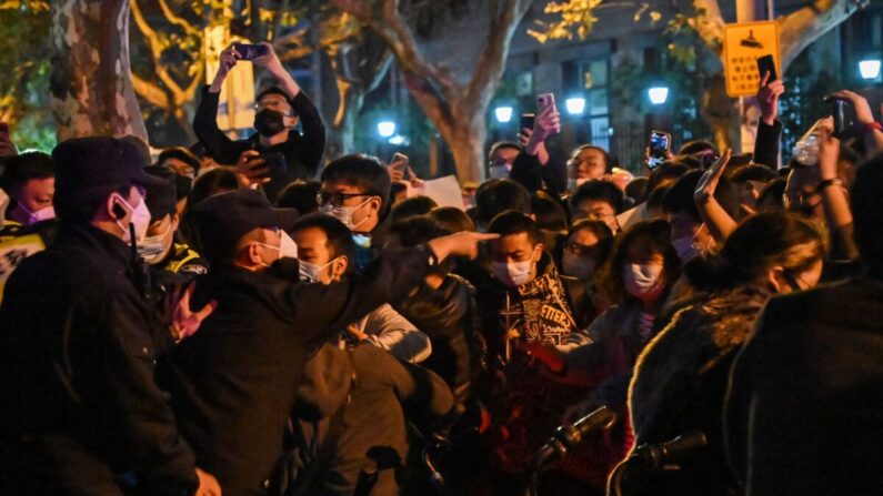 La policía y la gente se enfrentan durante una protesta contra la política de cero-COVID de China en Shanghai el 27 de noviembre de 2022. (Hector Retamal/AFP vía Getty Images)
