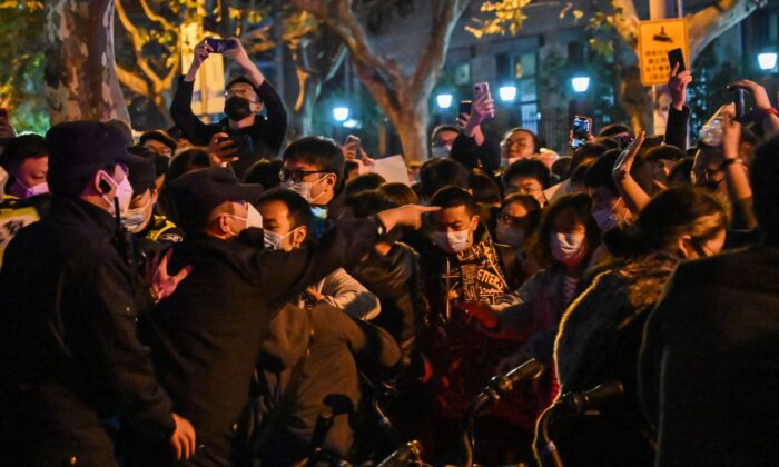La policía y la gente chocan durante una protesta contra la política de cero-COVID de China, en Shanghai, el 27 de noviembre de 2022. (Hector Retamal/AFP vía Getty Images)
