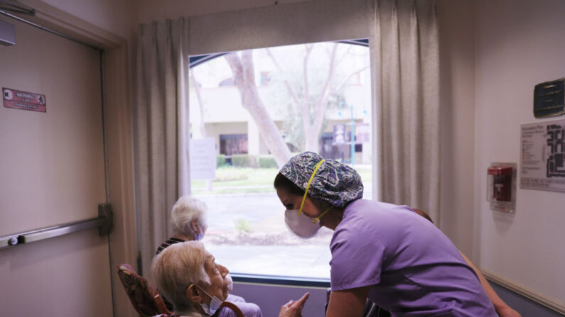 La directora ejecutiva, Margarita Kechichian, habla con los residentes reunidos junto a una ventana en la residencia de ancianos Ararat, en el barrio de Mission Hills, el 24 de marzo de 2021, en Los Ángeles, California. (Mario Tama/Getty Images)