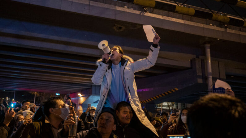 Los manifestantes gritan consignas durante una protesta contra las estrictas medidas de cero COVID de China el 28 de noviembre de 2022 en Beijing, China. Muchos culparon a las restricciones de COVID por las muertes durante un incendio. (Kevin Frayer/Getty Images)