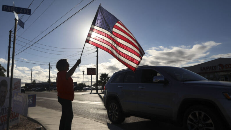 Una mujer agita una bandera estadounidense para saludar a los automovilistas que se dirigen a votar en las elecciones de mitad de período de Estados Unidos en el Centro Cultural César Chávez en San Luis, Arizona, el 8 de noviembre de 2022. (Sandy Huffaker/AFP vía Getty Images)
