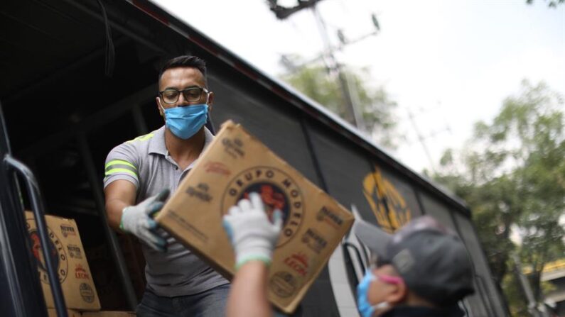 Dos trabajadores descargan cajas de cerveza en la Ciudad de México. Imagen de archivo. EFE/ Sáshenka Gutiérrez