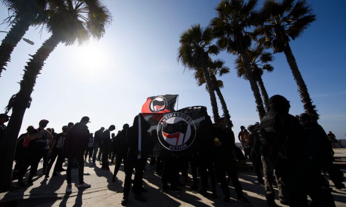 Contramanifestantes, algunos con banderas de Antifa, esperan antes de enfrentarse a una manifestación de la "Marcha Patriótica" en apoyo al entonces presidente Donald Trump en el barrio de Pacific Beach, en San Diego, el 9 de enero de 2021. (Patrick T. Fallon/AFP vía Getty Images)