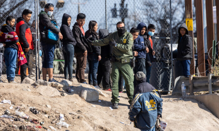 Un agente de la Patrulla Fronteriza de EE. UU. instruye a los inmigrantes que habían cruzado el Río Grande hacia El Paso, Texas, el 19 de diciembre de 2022 visto desde Ciudad Juárez, México. (John Moore/Getty Images)