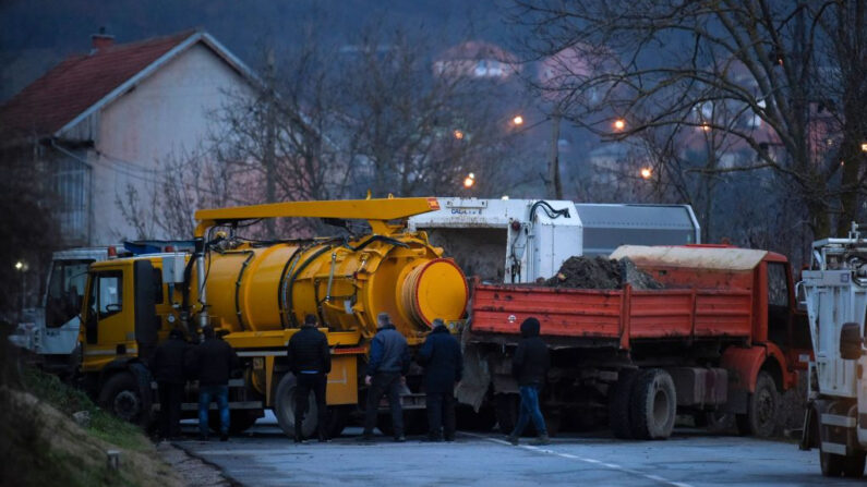 Varios transeúntes retiran camiones de una barricada instalada por serbios de etnia kosovar en el pueblo de Rudare, cerca de la ciudad de Zvecan (Kosovo), el 29 de diciembre de 2022. (Armend Nimani/AFP vía Getty Images)