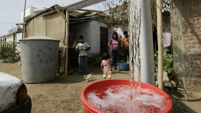 Fotografía de archivo en la que se registró a miembros de una familia al recibir agua potable suministrada por un camión cisterna, en el distrito Oasis de Villa, a unos 10 kilómetros al sur de Lima (Perú). EFE/Paolo Aguilar