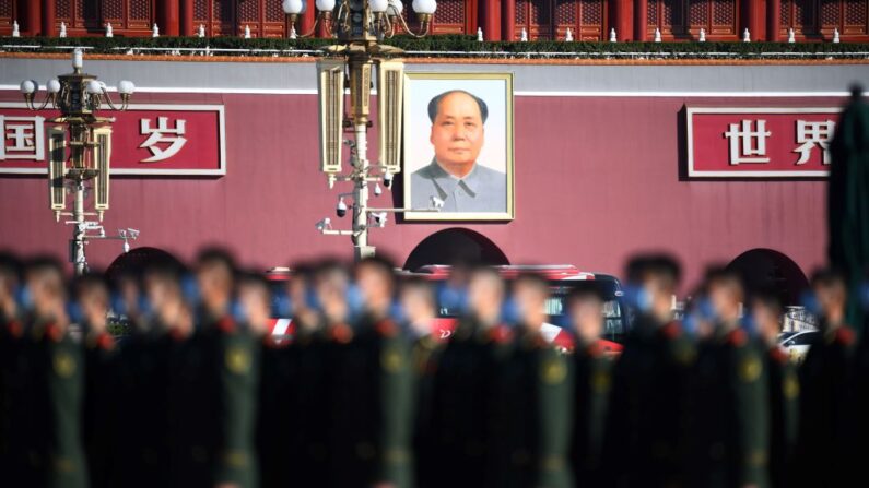 El retrato del difunto líder comunista, Mao Zedong, se ve detrás de policías paramilitares mientras se reúnen en la Plaza de la Paz Celestial de Beijing antes de una ceremonia que marcaba el 70 aniversario de participación de China en la Guerra de Corea el 23 de octubre de 2020 (Noel Celis/AFP vía Getty Images)