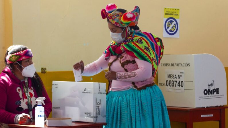 Una mujer vestida con un atuendo típico quechua deposita su voto en un colegio electoral en la comunidad rural andina de Capachica, cerca de la frontera con Bolivia, en Perú, el 6 de junio de 2021. (Juan Carlos Cisneros/AFP vía Getty Images)