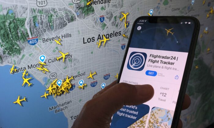 La aplicación Flightradar24 se ve en un smartphone delante de una pantalla que muestra la posición en directo de los aviones rastreados por la aplicación en la zona de Los Ángeles, California, el 5 de agosto de 2022. (Chris Delmas/AFP vía Getty Images)