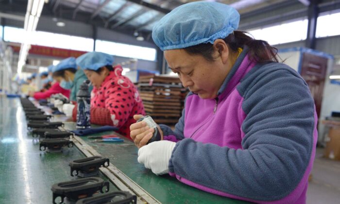 Un empleado trabaja en una cadena de montaje produciendo altavoces en una fábrica de la ciudad de Fuyang, en la provincia oriental china de Anhui, el 30 de noviembre de 2022. (STR/AFP vía Getty Images)