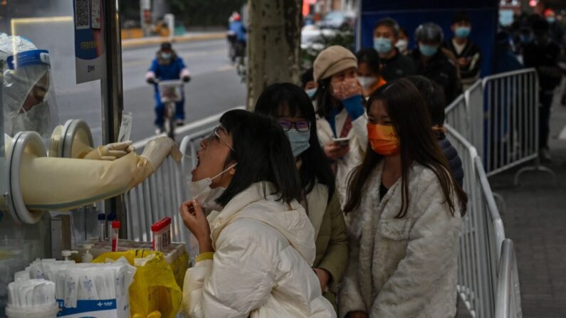 Un trabajador sanitario toma una muestra con un hisopo de una mujer para analizar la presencia de COVID-19 en el distrito de Jing'an en Shanghái, China, el 7 de diciembre de 2022. (Hector Retamal/AFP vía Getty Images)