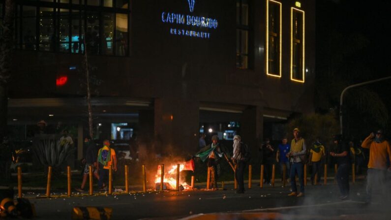 Los partidarios del presidente Jair Bolsonaro que protestan por la detención de un líder indígena chocan con la policía antidisturbios se enfrentan en Brasilia el 12 de diciembre de 2022. (EVARISTO SA/AFP via Getty Images)