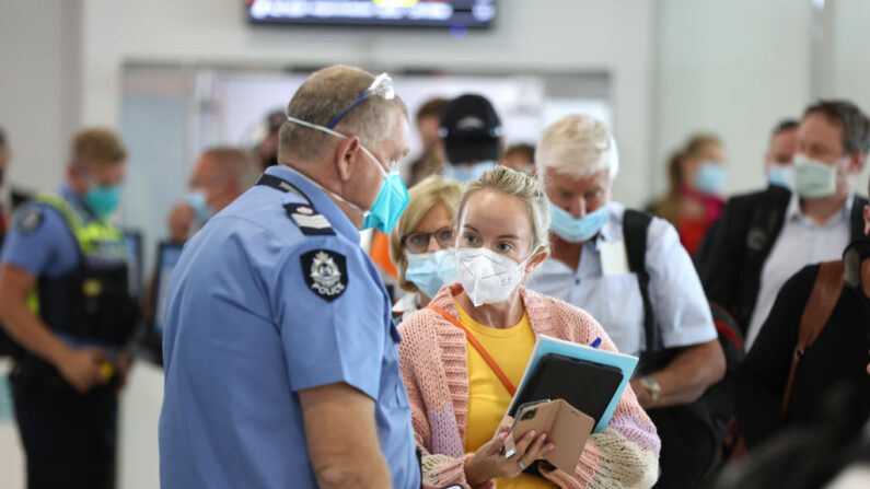 Los pasajeros que llegan hablan con un agente de policía de Australia Occidental en el aeropuerto nacional de Perth el 03 de marzo de 2022 en Perth, Australia. (Paul Kane/Getty Images)