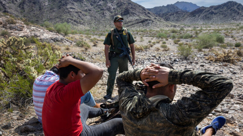 Un agente de la Patrulla Fronteriza de Estados Unidos vigila a un grupo de inmigrantes ilegales después de seguirles la pista a través de un terreno escarpado en el Monumento Nacional Organ Pipe, Arizona, el 28 de septiembre de 2022. (John Moore/Getty Images)
