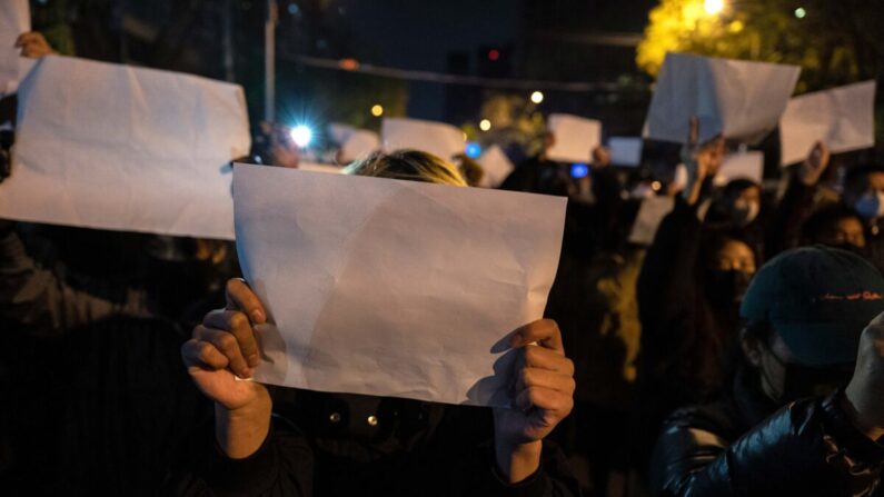 Los manifestantes sostienen un papel blanco contra la censura mientras marchan durante una protesta contra las estrictas medidas de cero-COVID de China en Beijing el 27 de noviembre de 2022. (Kevin Frayer/Getty Images)