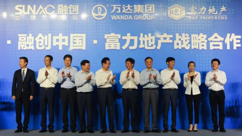 Directivos chinos de Wanda, de Sunac China Holdings Limited, y de R&F Properties, aplauden mientras asisten a la ceremonia de firma de la asociación estratégica entre Wanda Group, Sunac y R&F Properties Group, en Beijing, el 19 de julio de 2017. (WANG ZHAO/AFP a través de Getty Images)
