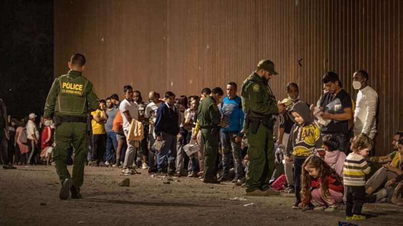 Agentes de la Patrulla Fronteriza de EE.UU. verifican la identificación de inmigrantes mientras esperan ser procesados ​​después de cruzar la frontera desde México, en Yuma, Arizona, el 22 de junio de 2022. (Qian Weizhong/VCG/Getty Images)