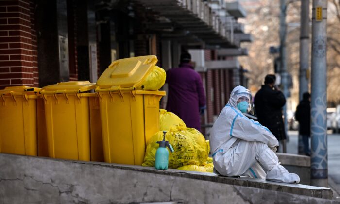 Un trabajador con equipo de protección personal se sienta junto a material de desecho fuera de una clínica de fiebre durante la pandemia de COVID-19, en Beijing, el 19 de diciembre de 2022. (Noel Celis/AFP a través de Getty Images)
