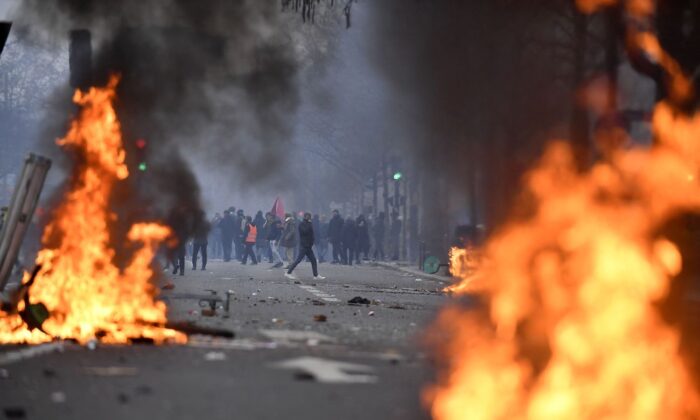 Manifestantes se paran detrás de las llamas durante los enfrentamientos que se produjeron tras una manifestación de miembros de la comunidad kurda, un día después de que un hombre armado abriera fuego en un centro cultural kurdo y matara a tres personas, en la Place de la Republique en París, el 24 de diciembre de 2022. (Julien de Rosa/AFP vía Getty Images)
