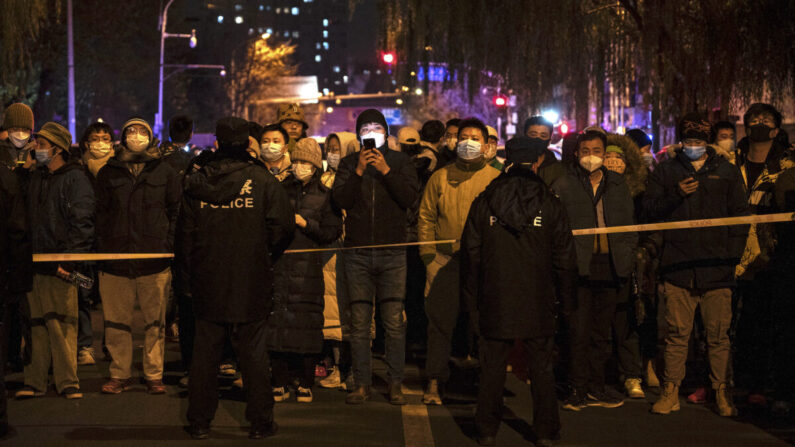 La policía mantiene a algunos manifestantes detrás de un cordón durante una protesta contra las estrictas medidas del régimen chino de cero-COVID, en Beijing, China, el 27 de noviembre de 2022. (Kevin Frayer/Getty Images)
