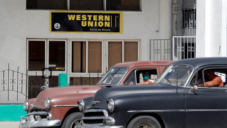 Dos autos clásicos pasan frente a una oficina de Western Unión en La Habana, Cuba. Imagen de archivo. EFE/Ernesto Mastrascusa