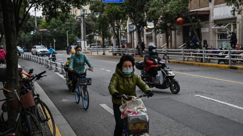 Varias personas montan en bicicleta en una calle del distrito de Jing'an, en Shanghái, el 7 de diciembre de 2022. (Hector Retamal/AFP vía Getty Images)
