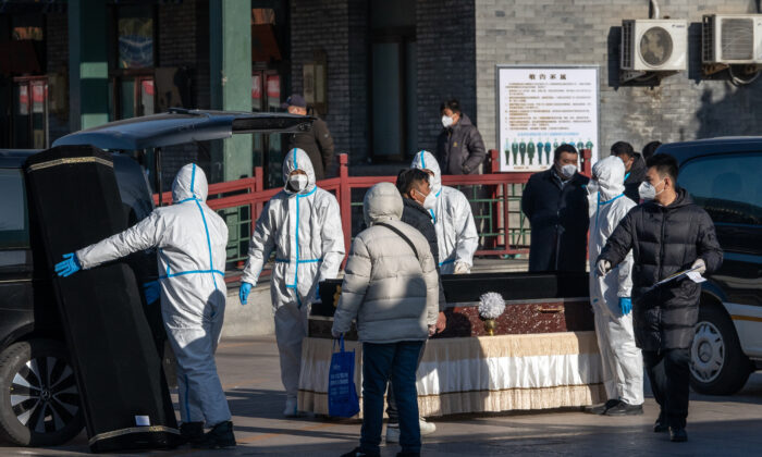 Trabajadores con equipo de protección manipulan un ataúd y una caja de ataúd en la funeraria Dongjiao, designada al parecer para ocuparse de las víctimas mortales del COVID-19, en Beijing, el 19 de diciembre de 2022. (Bloomberg vía Getty Images)