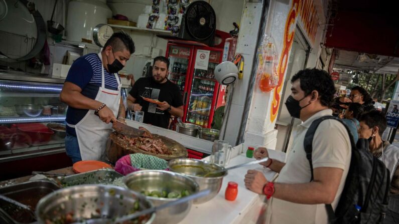 Gente come tacos en una taquería en una calle de Ciudad de México (México) el 20 de diciembre de 2022. (Nicolas Asfouri/AFP vía Getty Images)