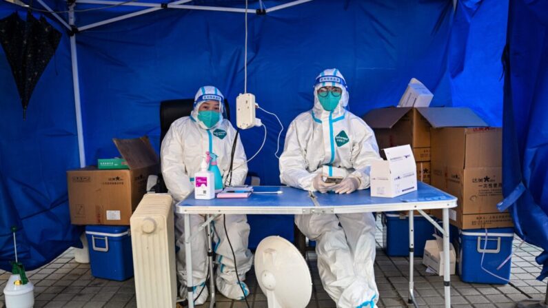 Trabajadores sanitarios esperan a que la gente escanee un código sanitario para hacerse la prueba del COVID-19 en el distrito de Jing'an en Shanghái, China, el 22 de diciembre de 2022. (Hector Retamal/AFP vía Getty Images)