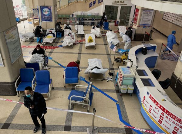 Un hombre se para frente a un área acordonada, donde los pacientes con COVID-19 yacen en camas de hospital en el vestíbulo del Hospital Popular No. 5 de Chongqing, en la ciudad de Chongqing, en el suroeste de China, el 23 de diciembre de 2022. (AFP a través de Getty Images)
