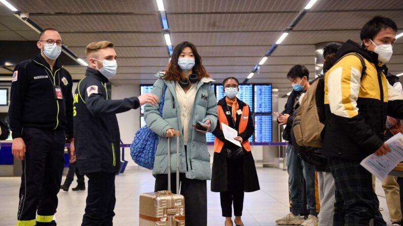 Pasajeros de un vuelo procedente de China esperan en una cola para comprobar sus documentos de vacunación contra el covid-19 como medida preventiva, tras llegar al aeropuerto de París-Charles-de-Gaulle en Roissy, a las afueras de París (Francia), el 1 de enero de 2023. (Julien De Rosa/AFP vía Getty Images)