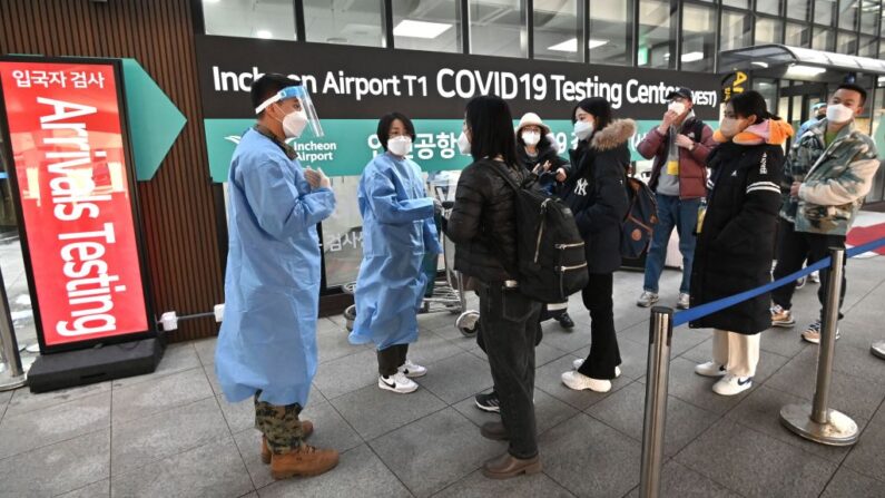 Trabajadores sanitarios guían a los viajeros procedentes de China frente a un centro de pruebas de covid-19 en el Aeropuerto Internacional de Incheon, al oeste de Seúl (Corea del Sur), el 3 de enero de 2023. (Jung Yeon-je/AFP vía Getty Images)