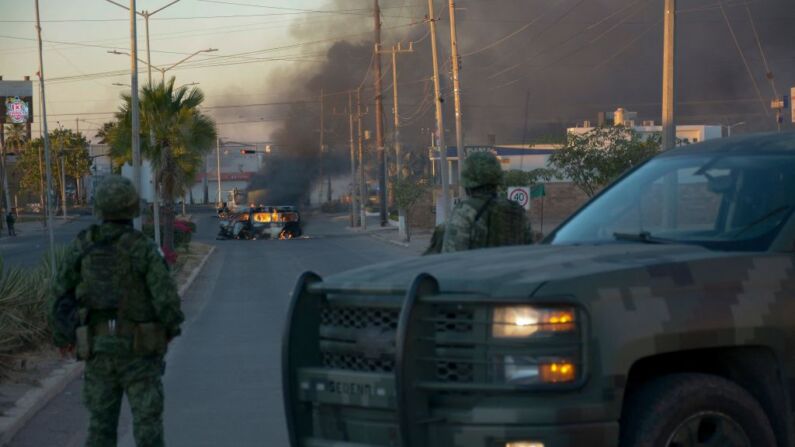 Soldados mexicanos montan guardia cerca de vehículos en llamas en una calle durante una operación para detener al hijo de Joaquín "El Chapo" Guzmán, Ovidio Guzmán, en Culiacán, estado de Sinaloa, México, el 5 de enero de 2023. (Foto de JUAN CARLOS CRUZ/AFP a través de Getty Images)